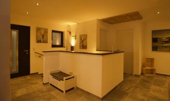 A bright and modern foyer with stylish interior. There is a reception desk, pictures on the walls, and a cozy seating area.