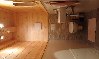 A modern toilet with wooden walls and bright tiles. The room is well-lit and contains a sink as well as a mirror.