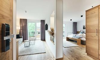 A modern bedroom with hardwood floors and large windows. The living room is bright and inviting, with cozy furnishings and a beautiful view.