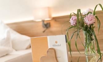 A beautiful room with a bouquet of flowers and a heart-shaped card. The soft lighting creates a cozy atmosphere.