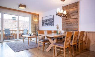 A cozy dining area with a large wooden table and chairs. The window offers a view of the balcony and provides plenty of natural light.