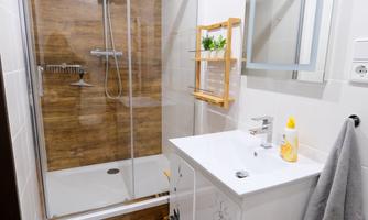 A modern bathroom with a glass shower and a stylish sink. The walls are tiled in light colors, and wooden details create a warm atmosphere.