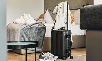 A cozy room with a bed, suitcase, and sports shoes. The atmosphere is inviting and modern.