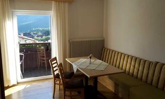 A bright room with a table and a bench. Through the window, there is a beautiful view of the mountains.