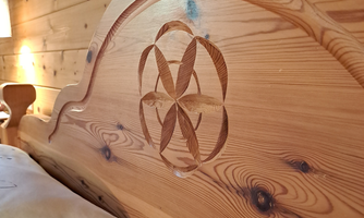 An artistically carved wooden headboard with a creative pattern. The warm wood color adds a cozy atmosphere to the room.
