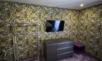 A modern room with a colorful floral pattern on the wall. There is a TV, a dresser, and a clothes rack.