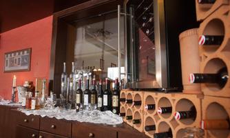 An elegant wine rack with various bottles and glasses. The room has a warm atmosphere and offers a nice selection of drinks.