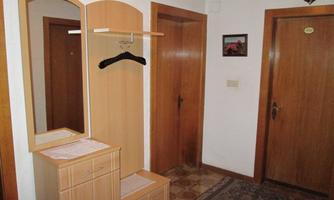 A hall with a wooden closet and a mirror. There are two doors and a carpet on the floor.