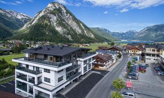 Modern buildings in a picturesque mountain landscape. In the background, green meadows and majestic mountains can be seen.