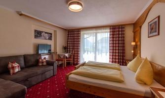 A cozy room with two beds and a sofa bed. Large windows provide plenty of natural light and access to the balcony.