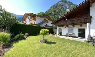 A beautiful house with a well-maintained garden and a view of the mountains. The surroundings are green and inviting, ideal for relaxing.