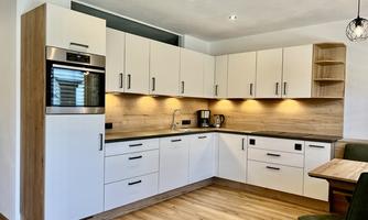 Modern kitchen with white cabinets and wood accents. A bright, inviting atmosphere with space for a small seating area.