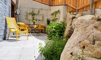 A beautiful courtyard with colorful garden furniture and plants. Mountains can be seen in the background.