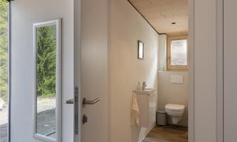 A modern bathroom with neutral tones and a large mirror. Daylight flows through the window, creating a relaxed atmosphere.