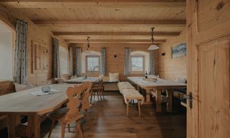 A cozy room with wooden furniture and large windows. The room is bright and inviting, ideal for social gatherings.