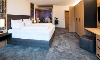 A modern bedroom with a large bed and cozy furnishings. This includes wooden wardrobes and a flat-screen TV.