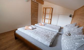 A cozy bedroom with two single beds and elegant bedding. The room features a warm wood look and a friendly atmosphere.