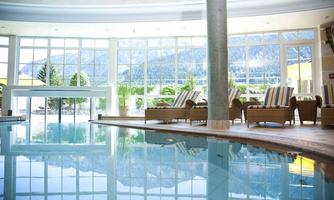 An elegant wellness area with a swimming pool and comfortable loungers. Large windows offer a view of the mountains and provide plenty of natural light.