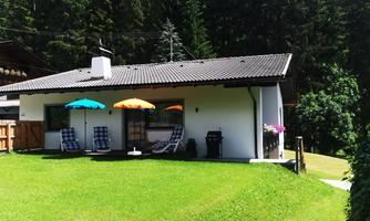 A comfortable house with a large garden and garden furniture. Colorful sunshades provide shade in a green, peaceful environment.