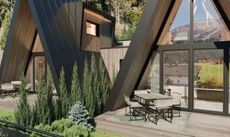 Modern cabins with pointed roofs, surrounded by green trees. Inviting terraces with seating offer a view of nature.