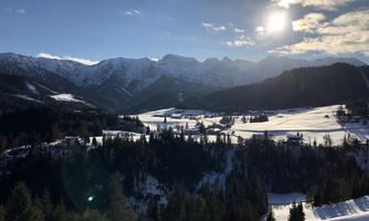 A beautiful winter landscape with snow-covered hills and mountains. The sun is shining and the sky is clear.