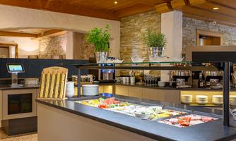 A modern breakfast buffet with fresh fruits and various dishes. The room has an inviting atmosphere with wooden details.