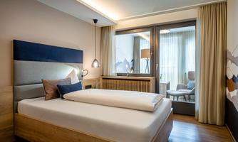 A modern bedroom with a cozy bed and a large window. The room is bright and cheerfully decorated.