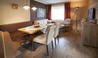 A cozy living space with a dining table and chairs. The decor is modern and inviting, with a window that lets in daylight.