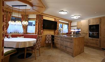 A modern kitchen with wooden cladding and stylish furniture. A round table with chairs invites you to eat.