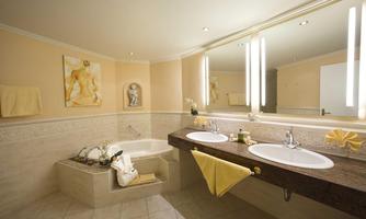 An elegant bathroom with a bathtub and two sinks. The walls are painted in warm tones and adorned with decorative elements.