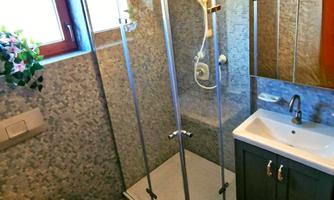 A modern bathroom with a glass shower, a sink, and a toilet. The room has a bright and friendly atmosphere.