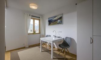 A bright workspace with a modern table and two chairs. Large windows provide a view of the mountains and let in plenty of light.