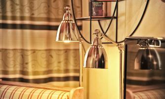 A cozy living area with a modern lamp and a mirror. The decorative curtains add an inviting atmosphere to the room.