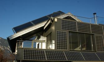 A modern house with solar panels on the roof and facade. The clear blue sky creates a pleasant overall image.