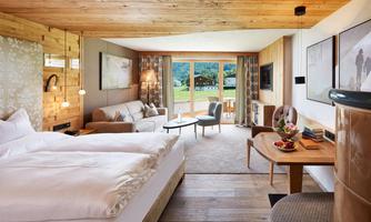 A modern room with wood decor, a comfortable bed, and a cozy living area. Large windows offer a beautiful view of the landscape.