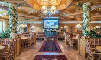 A cozy restaurant with wooden furniture and a warm atmosphere. The space is decorated with plants and can accommodate many guests.