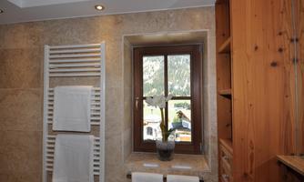 A modern bathroom with a window view of the mountains. Towels hang on a metal towel rack.
