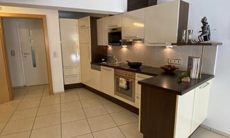 A modern kitchen with bright cabinets and an elegant countertop. It is well-equipped and feels inviting.