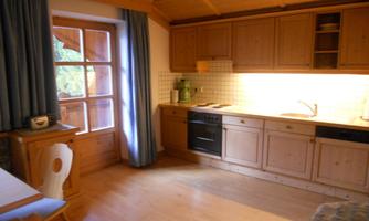 A bright kitchen with wooden cabinets and a window. The room has a cozy atmosphere with a table and chairs.