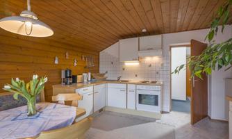 A bright kitchen with wood paneling and modern appliances. A table with fresh flowers creates an inviting atmosphere.