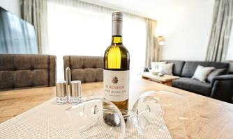 A bottle of white wine is on a table with two glasses. In the background, you can see a cozy sitting area.