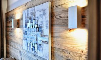 A modern wall decoration with an abstract artwork, surrounded by wooden panels. Soft wall lights create a pleasant atmosphere.