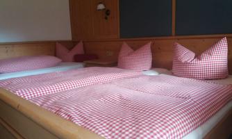 A cozy bedroom with a double bed and red check patterns. The pillows are in the same pattern, adding an inviting atmosphere to the room.
