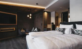 A modern hotel room with a large bed and elegant decoration. The room is bright and inviting, equipped with a television and a cozy seating area.