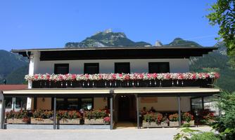 A picturesque building with lush flower boxes and a beautiful mountain in the background. The clear blue sky creates an inviting atmosphere.
