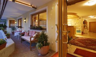 An inviting entrance area with a bright door and cozy seating. Flowers and plants create a friendly atmosphere.