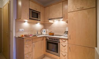 A modern kitchen with wooden cabinets and a stainless steel sink. It is well-equipped with a stove, microwave, and kettle.
