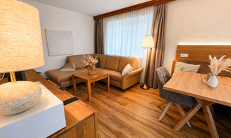A cozy living room with a comfortable sofa and a dining table. The decor is modern and welcoming, with plenty of natural light.