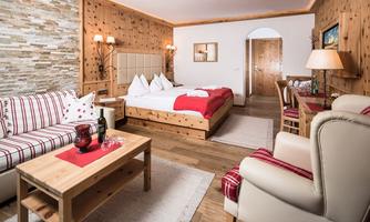 A cozy hotel room with wooden decor, a large bed, and a seating area. The room is warm and inviting, with stylish furniture and soft lighting.