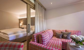 A cozy room with a sleeping area and a living room. Cozy, checkered furniture and bright colors create an inviting atmosphere.